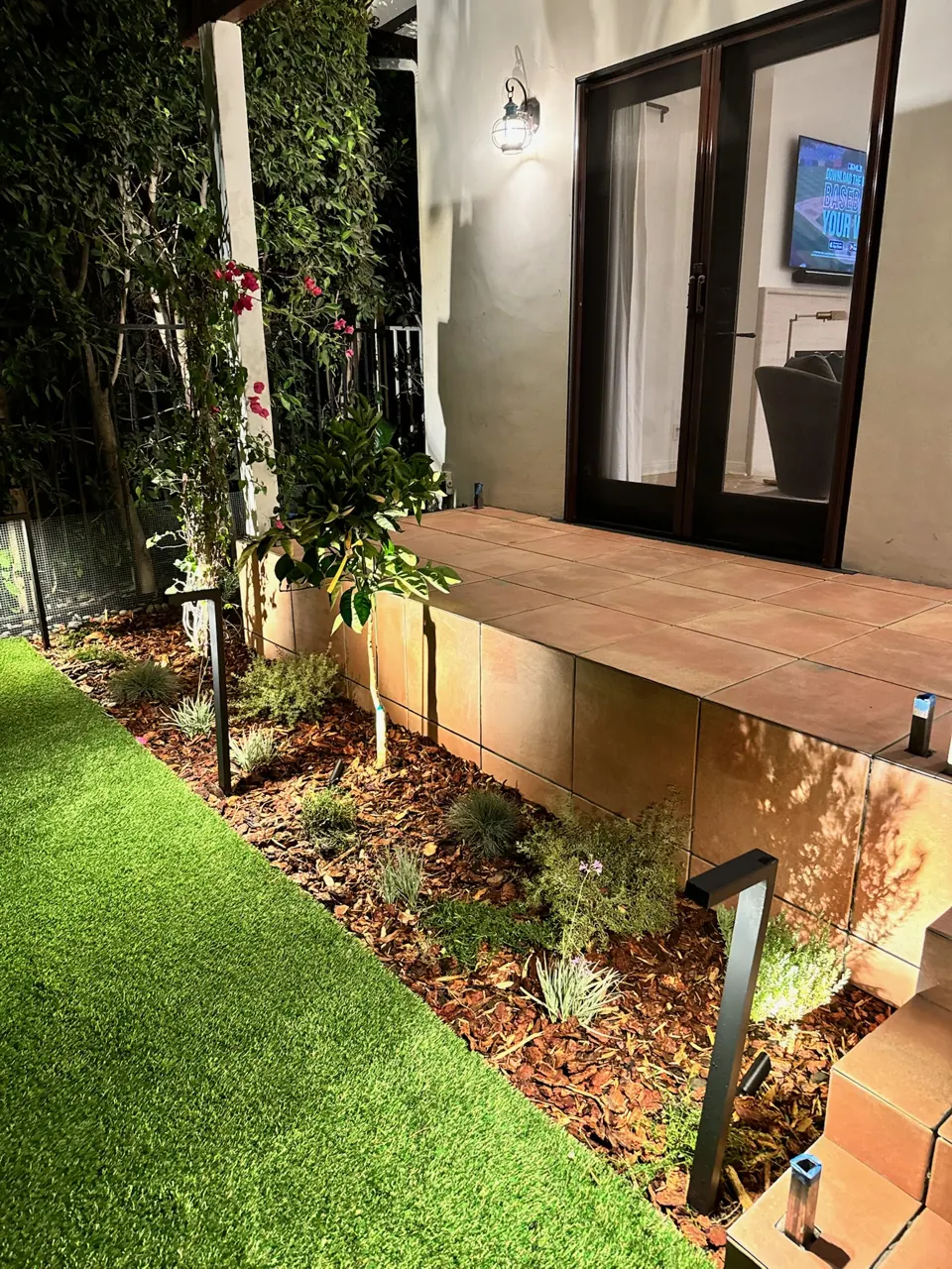 Path lights along a new lawn strip and planting bed at night