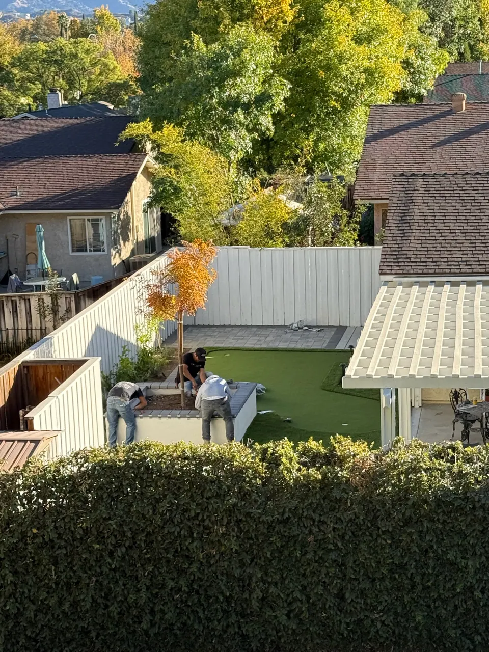 A crew laying turf beside a patio cover, seen from above