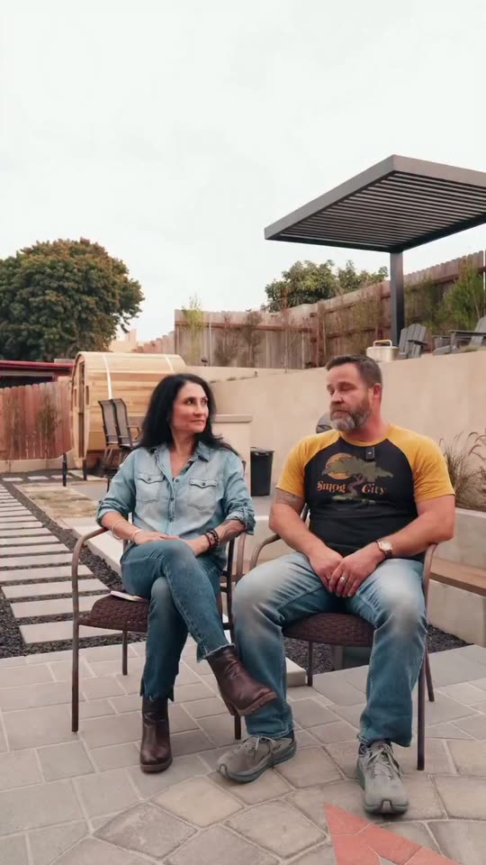 Two homeowners seated on their new patio under a pergola